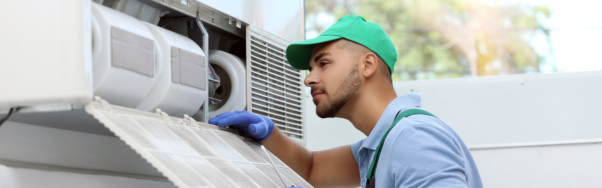 Professional technician maintaining modern air conditioner indoors